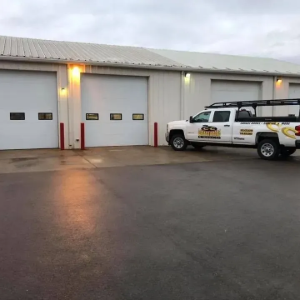 White service truck parked beside garage doors at a warehouse loading area at dusk