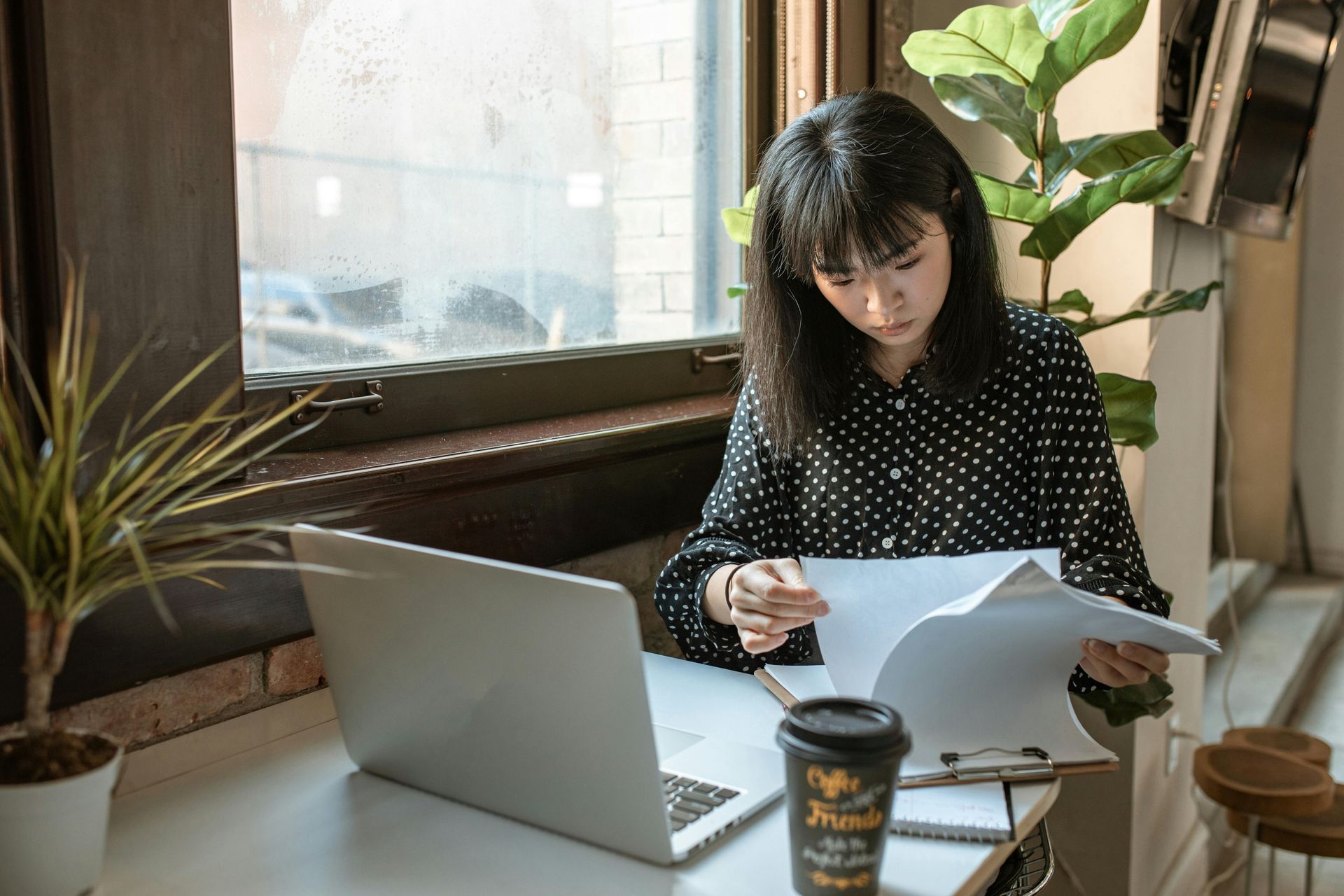 A woman is sitting at a desk with a laptop and a cup of coffee.