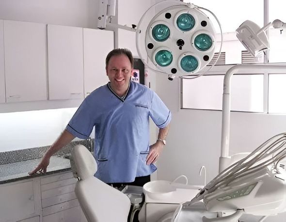 Mujer sonriente sosteniendo alineadores dentales transparentes sobre un fondo azul suave.