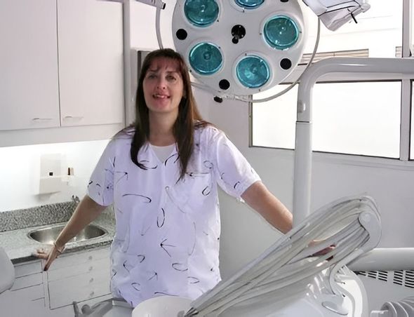 Durante un examen, un dentista le muestra a un paciente sonriente un modelo dental.