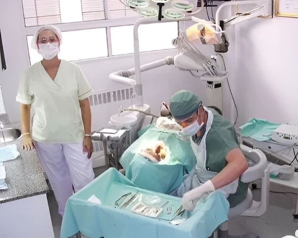 Manos ajustando un dispositivo médico iluminado en azul dentro de una cámara de instrumentos de laboratorio.