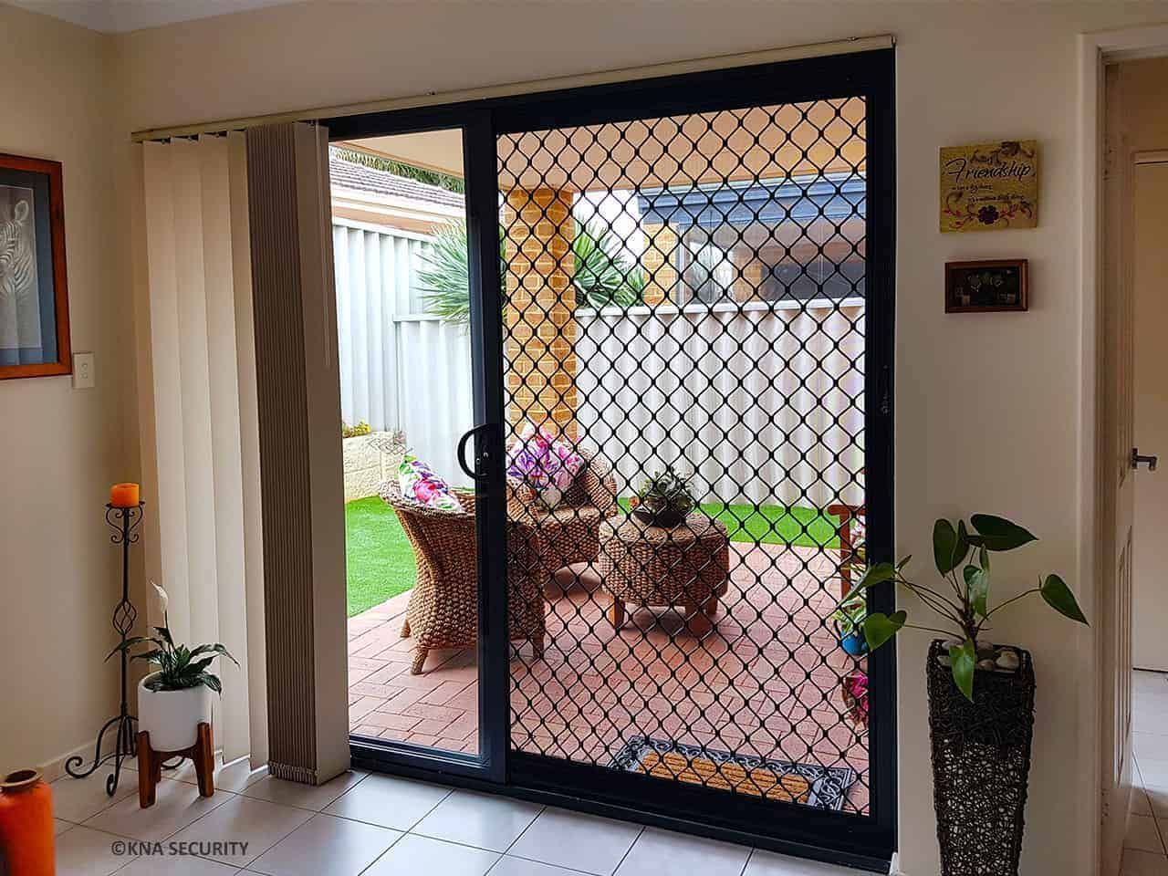 Living room opening to a patio with a table, chairs, and potted plants behind a mesh screen door