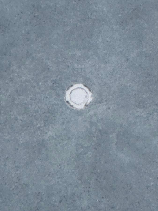 Close-up of a blue-gray surface with a small, white circle in the center, possibly a hole.
