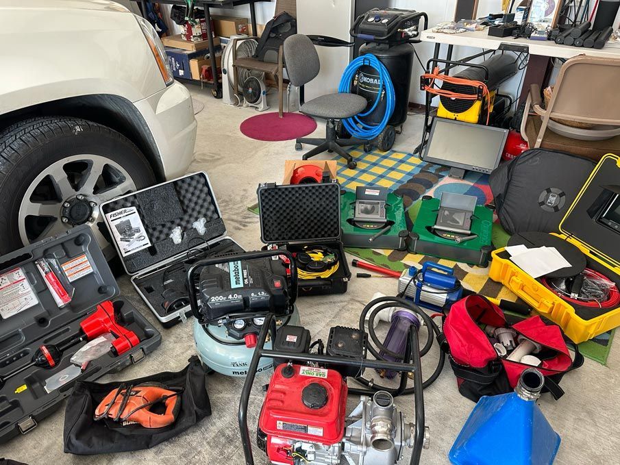 Various tools and equipment on a garage floor, including a generator, cases, and an SUV tire.