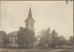 Sepia-toned church with tall steeple, surrounded by trees in a rural setting.