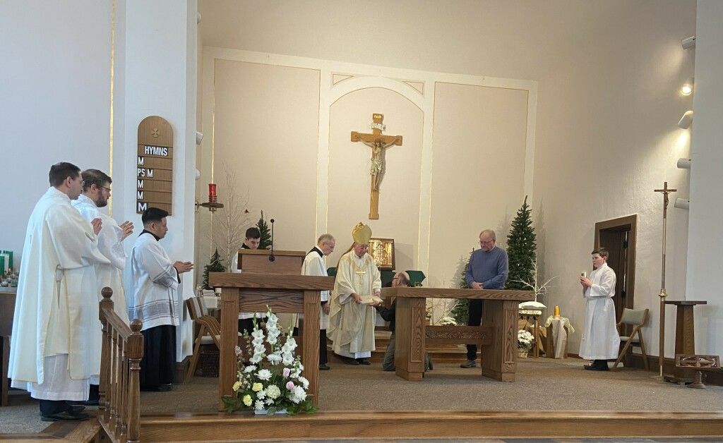 Church altar service with clergy in white robes and a crucifix at the center