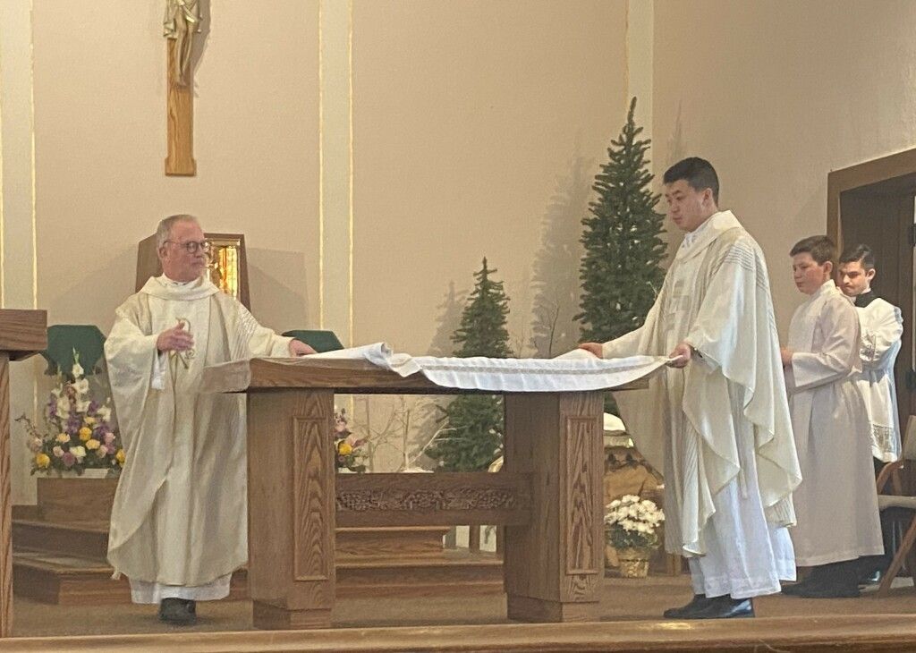 Priest and altar servers standing at a church altar during a religious service