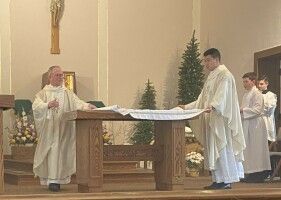 Priest celebrating Mass at the altar with altar servers in a church sanctuary