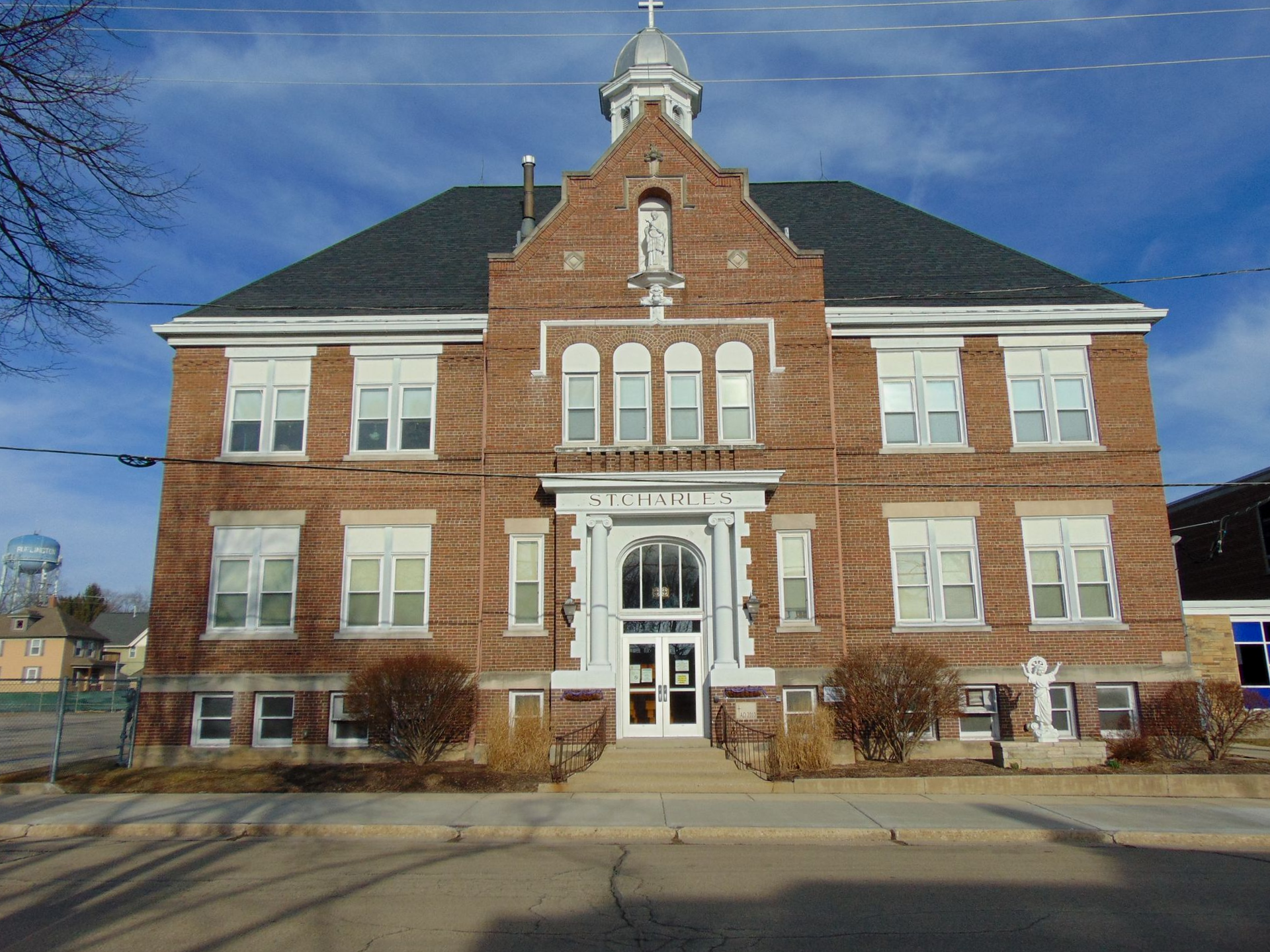 Front view of a two-story red-brick building with white trim and a central entrance under a blue sky