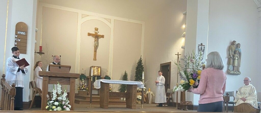Church altar service with priest, altar servers, and congregants in a small chapel