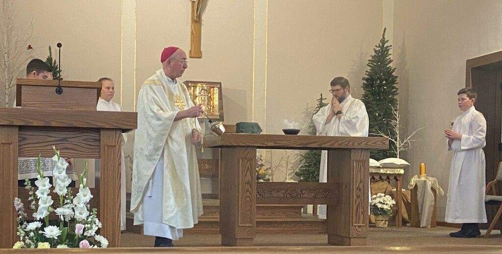 Priest celebrating Mass at an altar in a church, with two altar servers standing nearby