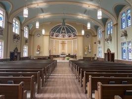 Church interior with wooden pews, arched ceiling, and altar at the far end.