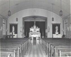 Church interior with rows of pews facing an altar at the far end