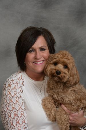 Woman holding a fluffy tan dog against a gray studio backdrop