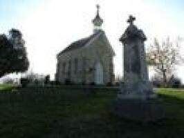 Stone church and monument silhouetted on a grassy hill at dusk
