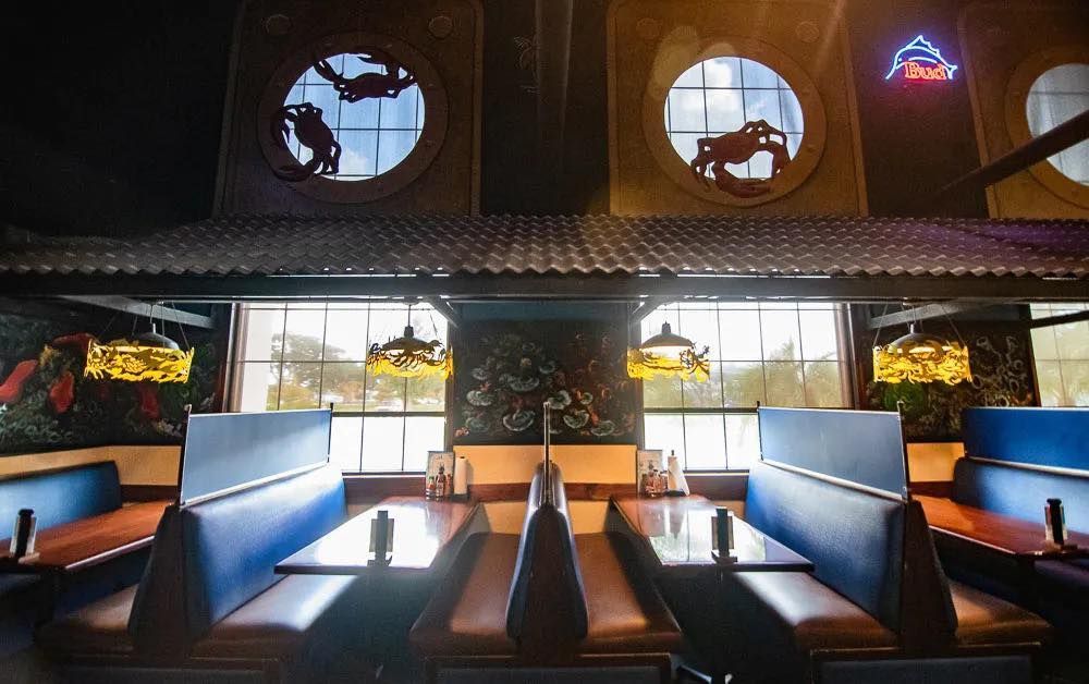 Restaurant interior with blue booths, tables, and decorative windows. At High Tide Harry's