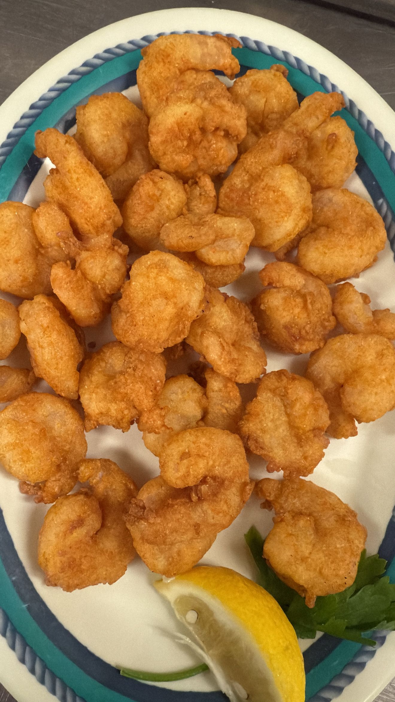 Plate of fried shrimp with lemon wedge and parsley. At High Tide Harry's