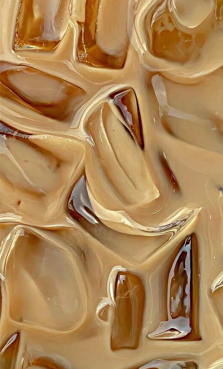 Close-up of iced coffee with large ice cubes, light brown liquid, and a glossy sheen.