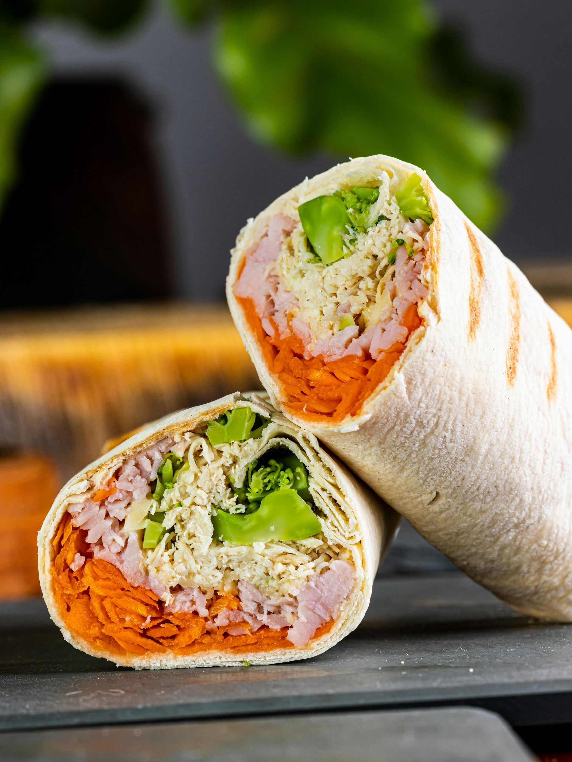 Cut wrap sandwich with carrot, ham, lettuce, and white sauce.