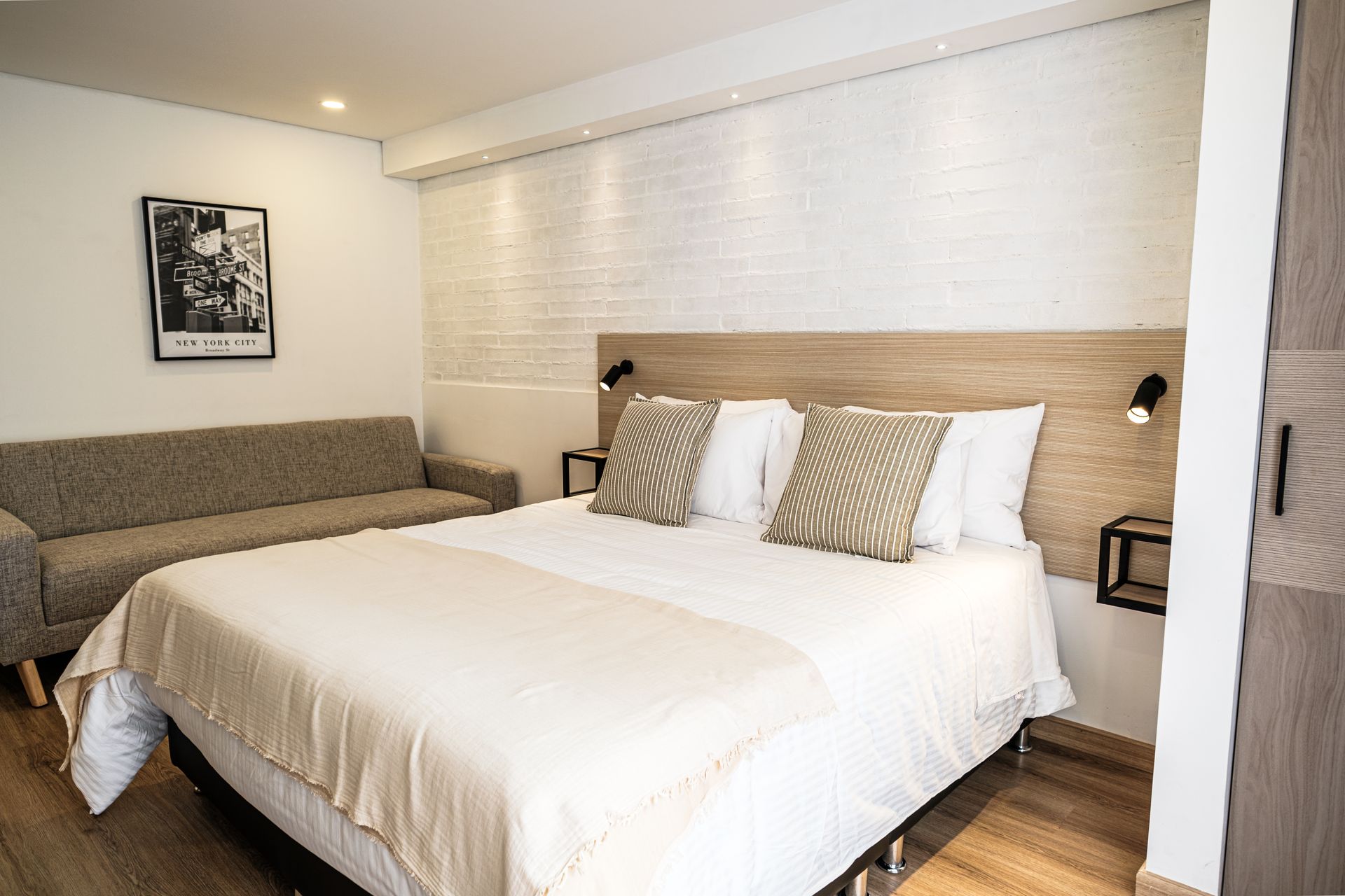 Apartasuites in Bogotá with double bed, spacious sofa, large window, and outdoor view.