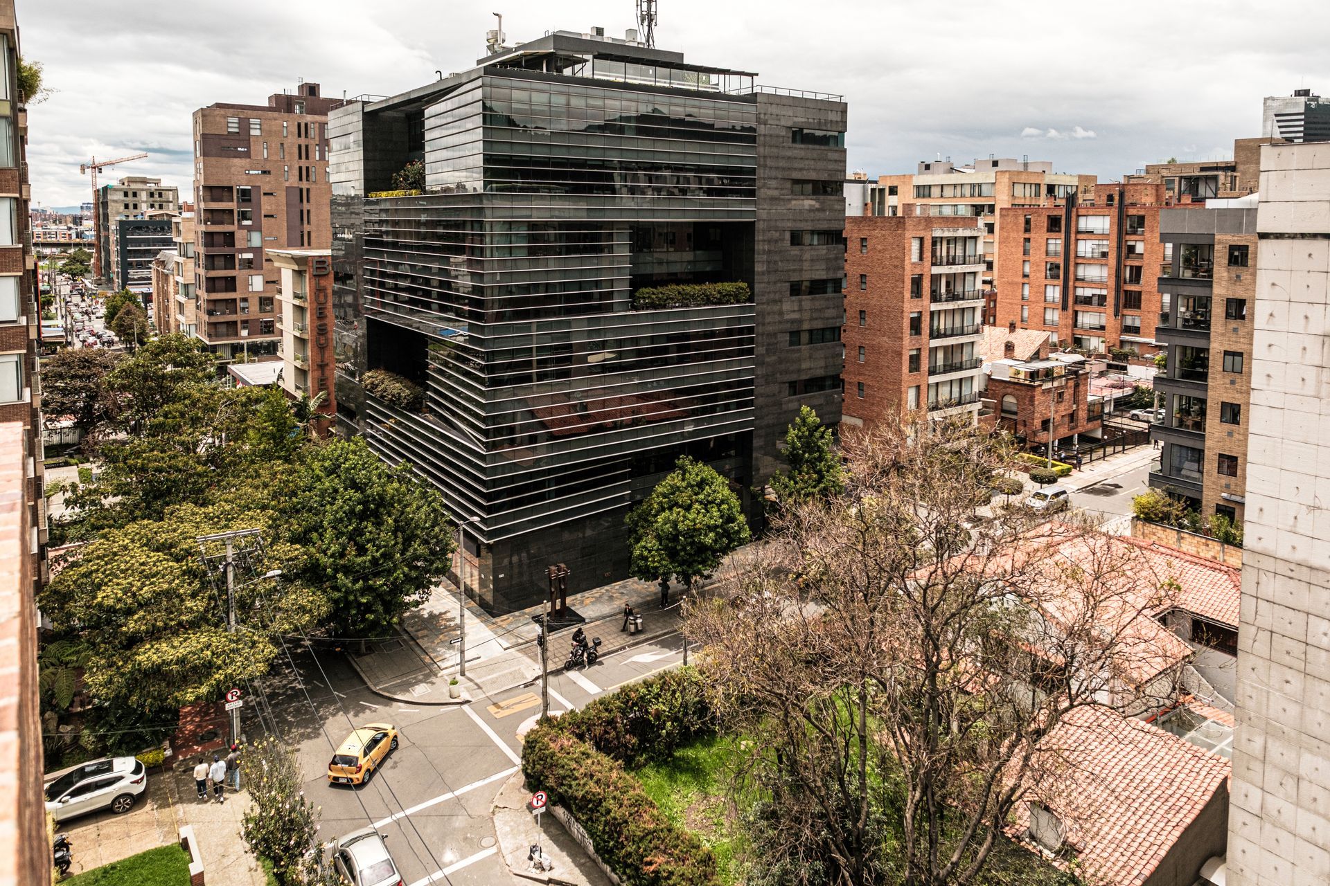 hotel ejecutivo Bogotá Nova Iorque con fachada oscura, edificios cercanos, árboles y vista urbana