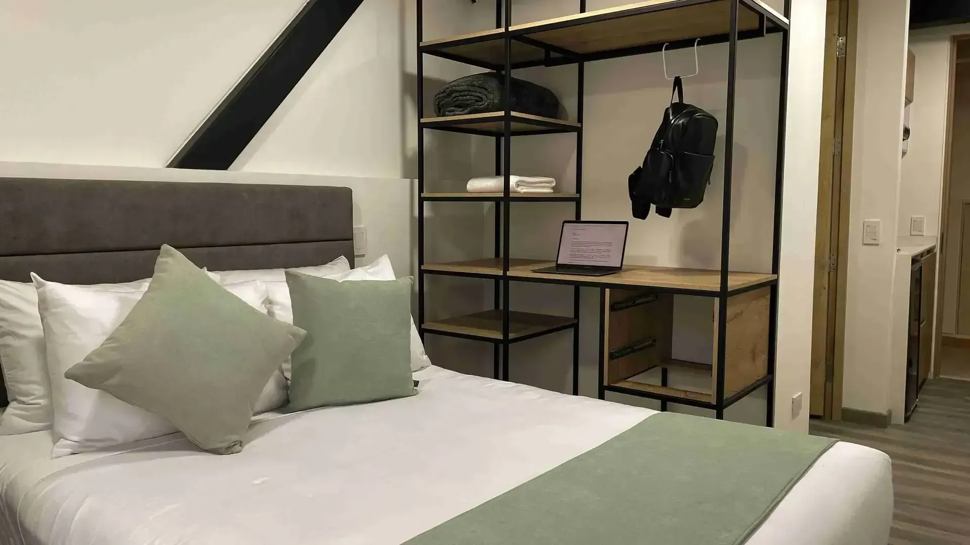 Habitación con cama doble, clóset abierto y escritorio en Nova Iorque, apartasuites en Bogotá para estadías cómodas.