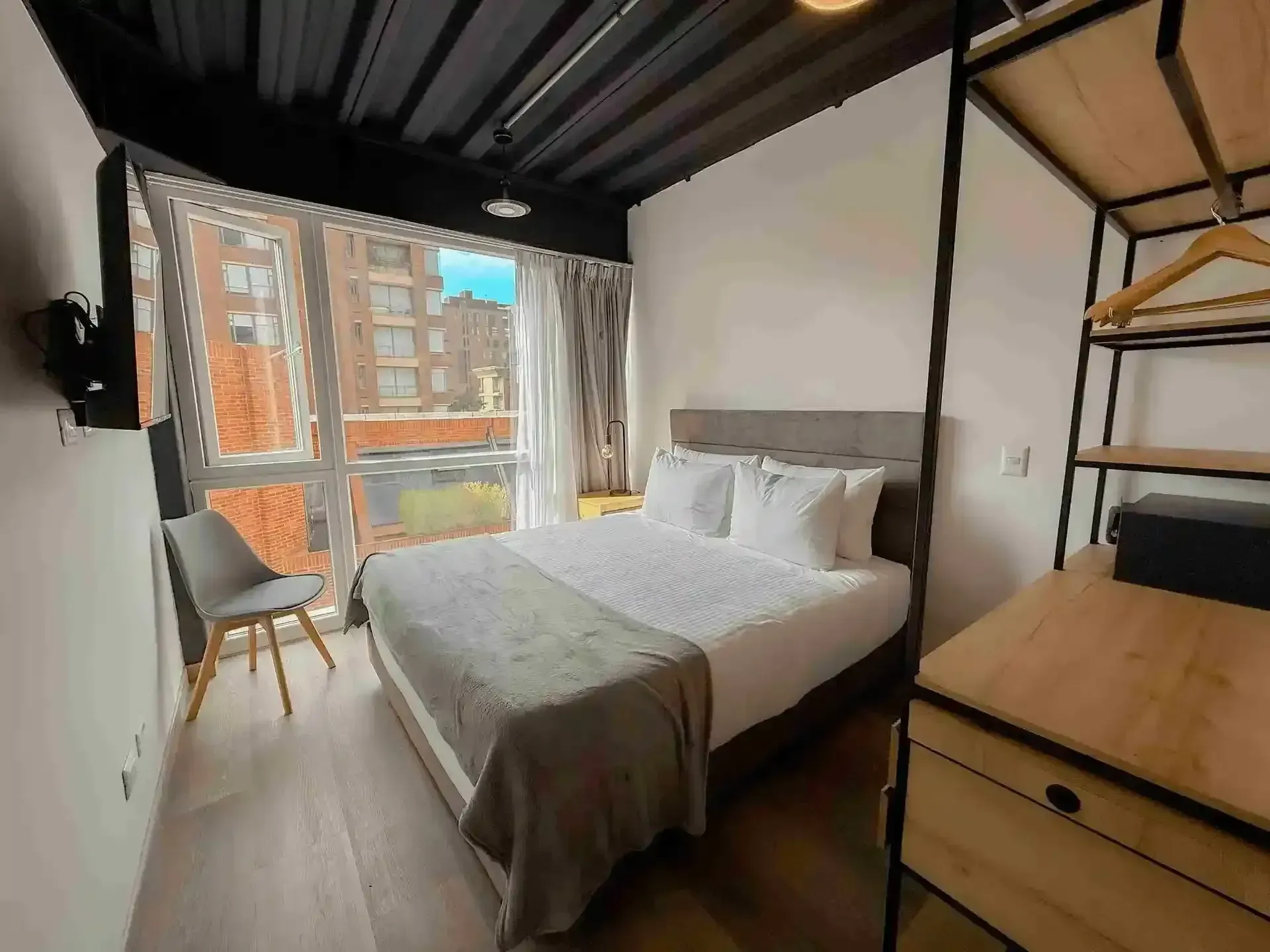 habitaciones en bogotá, con cama doble, televisor, armario en madera y vista a la ciudad