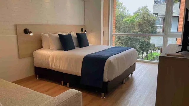 Apartasuites en Bogotá, con habitación de cama doble, ventanal y vista exterior en Nova Iorque.