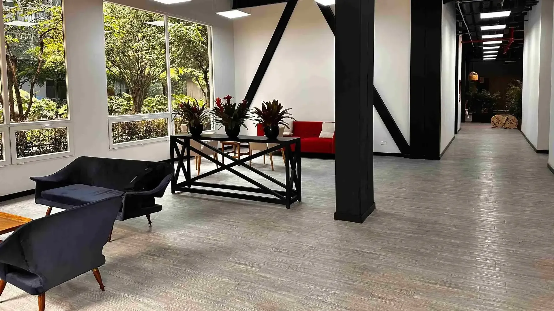 Nova Iorque, apartasuites en Bogotá, con recepción de ventanales amplios, sillones, mesas auxiliares y flores decorativas.