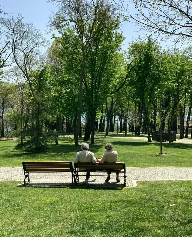 Pareja sentada en una banca rodeada de árboles, idea de qué hacer con tu pareja en Bogotá.