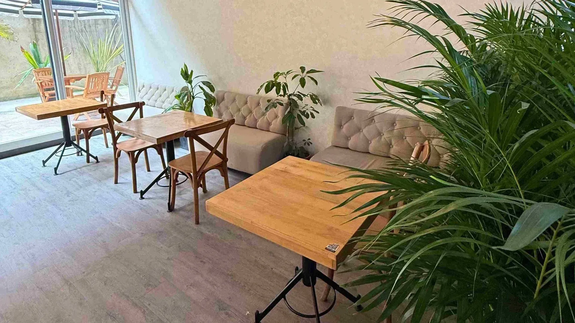 Nova Iorque, hotel con restaurante en Bogotá, con mesas de madera, sillas tapizadas y plantas al rededor.