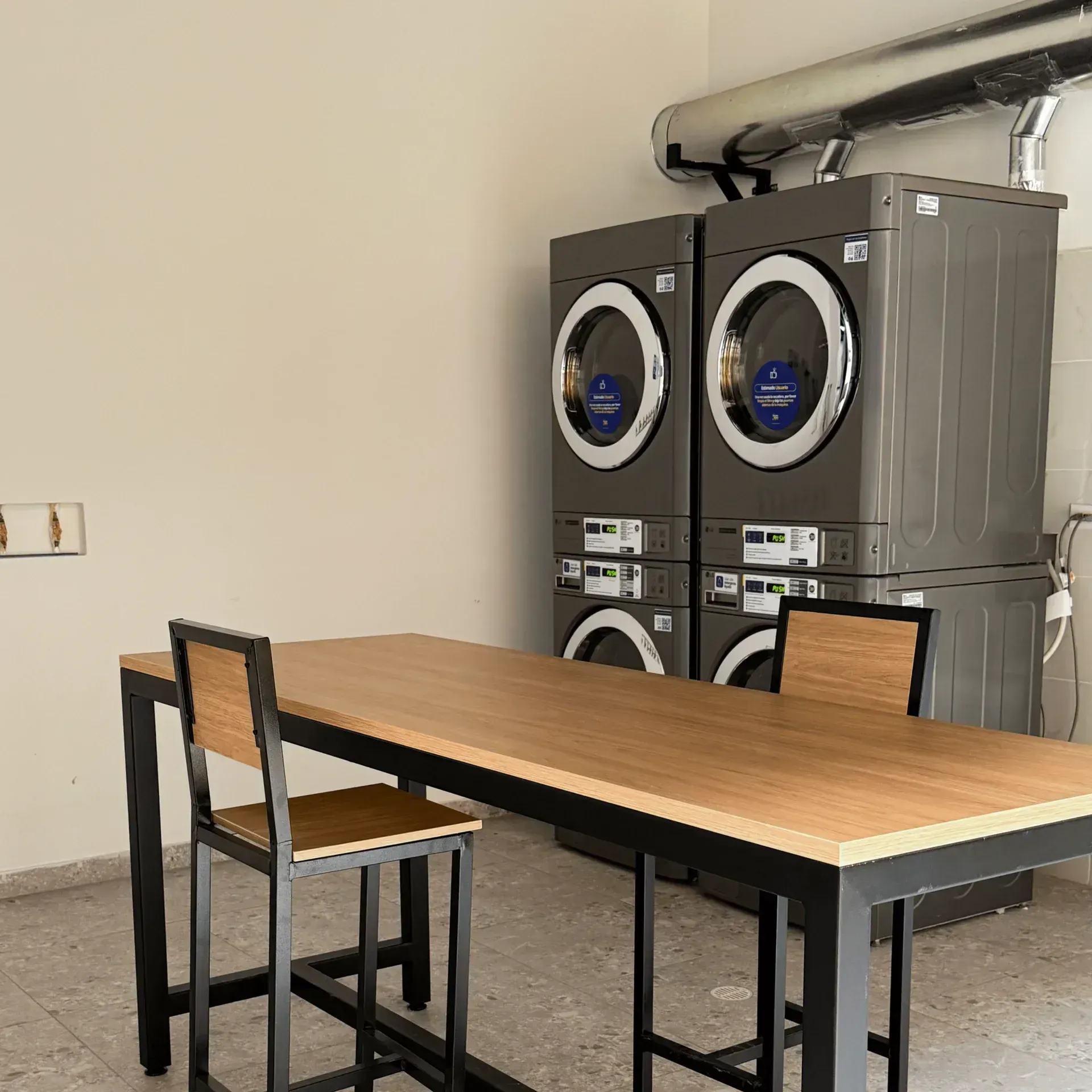 Self-service laundry area with washing and drying machines inside a hotel in Bogotá.