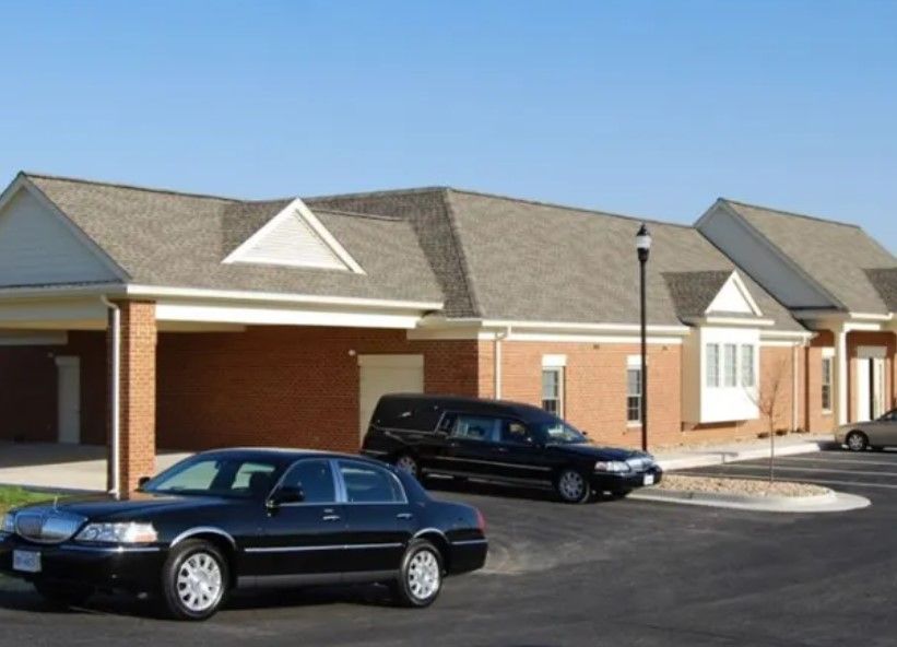A funeral home and parked vehicles show professional care from trusted Roanoke, VA funeral homes