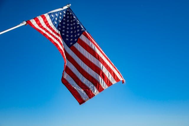 An American flag waves against a clear blue sky, a symbol of honor and remembrance with Roanoke, VA cremations