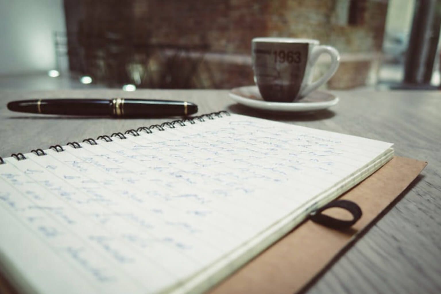 A notebook and coffee cup beside a pen create a quiet and reflective setting for Roanoke, VA funeral homes