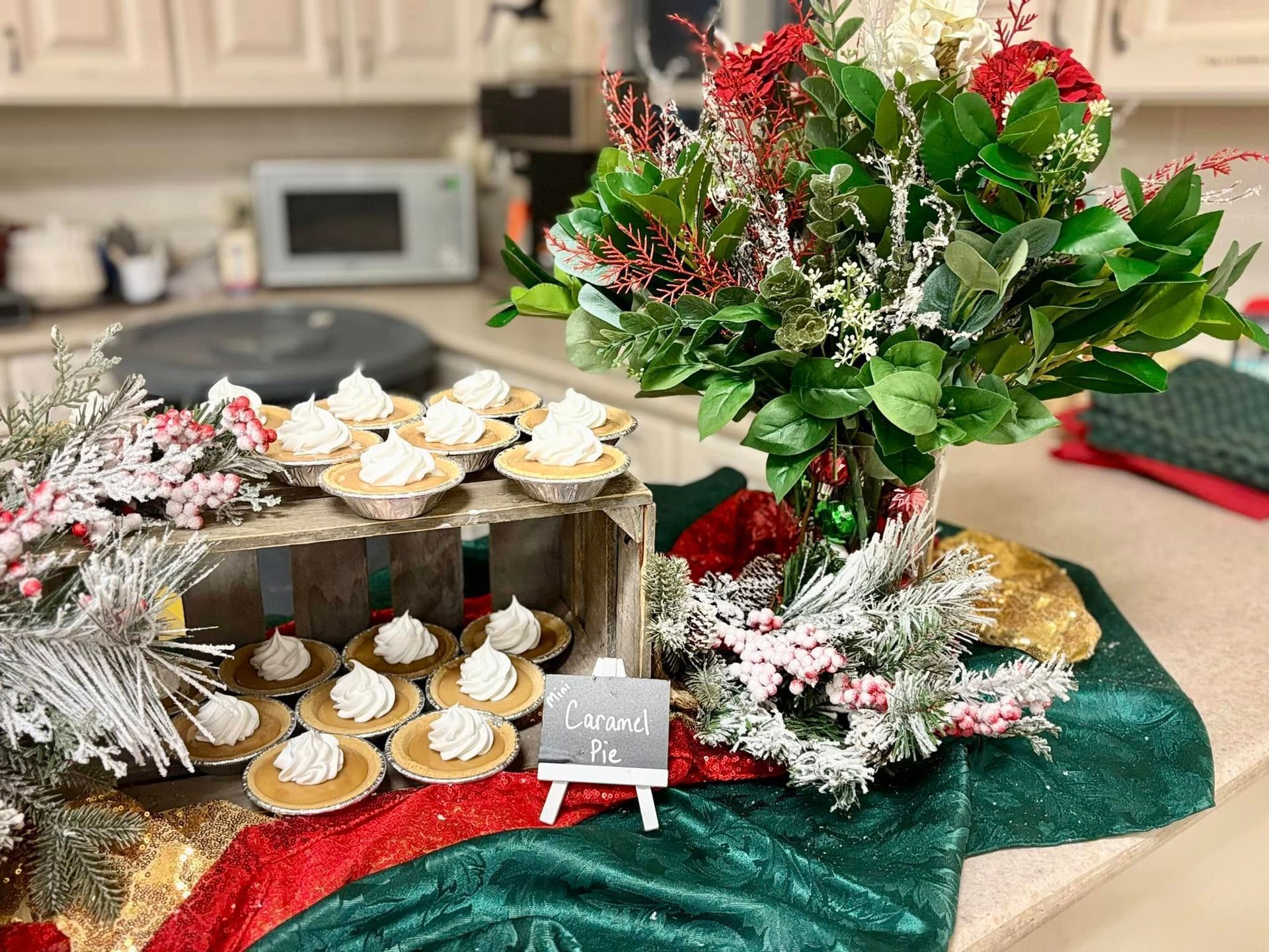 A table with mini pies, and christmas floral and frosted pine sprig decorations.
