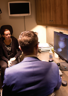 A man and a woman are sitting in front of a computer monitor
