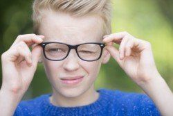 A young boy wearing glasses is making a funny face.