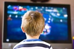 A young boy is sitting in front of a television playing a video game.