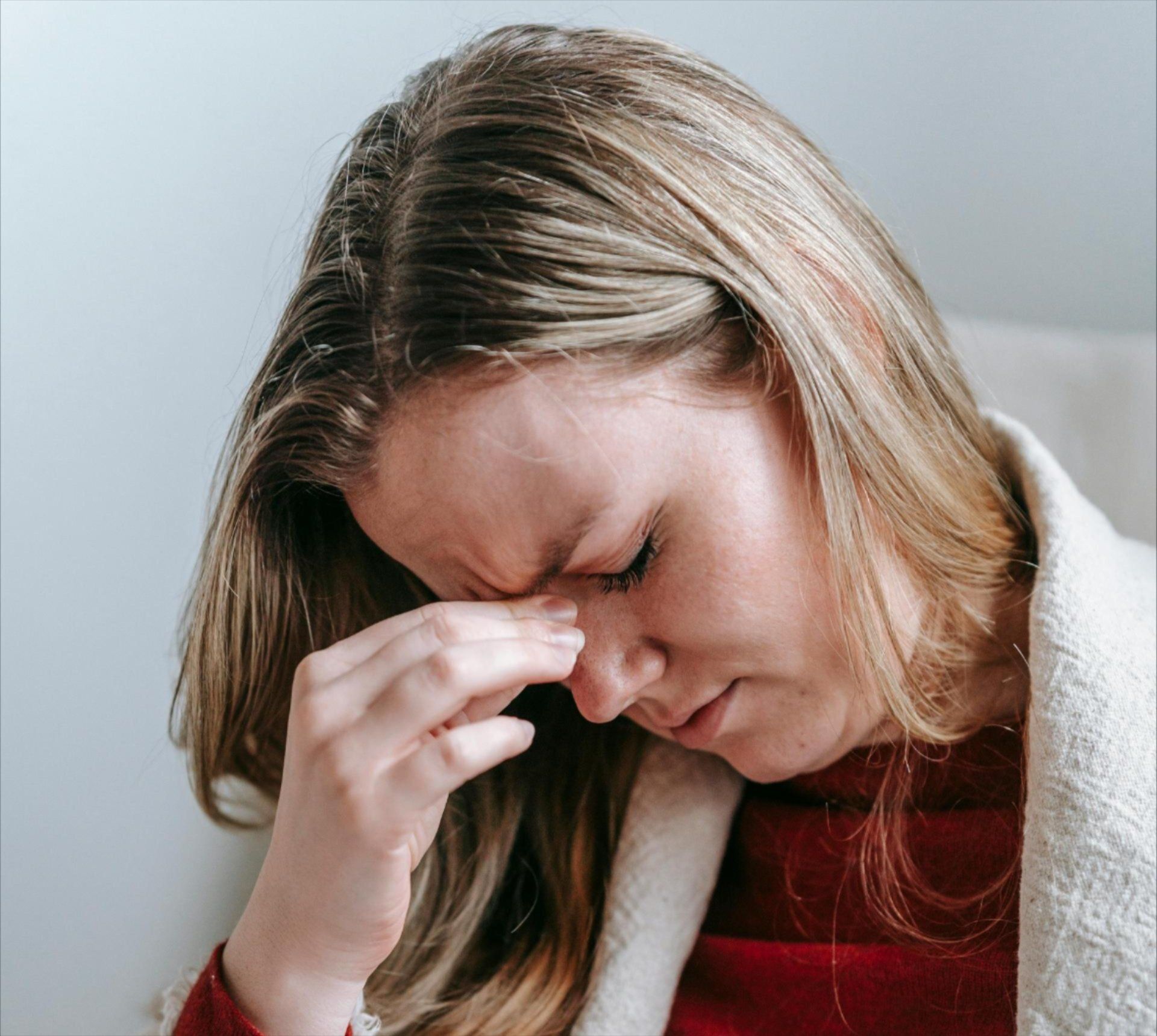 A woman is holding her nose because she has a headache.