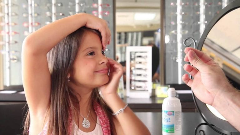 A little girl is looking at herself in a mirror.