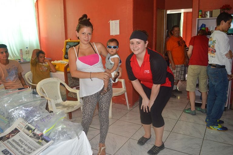 A woman is holding a baby while standing next to another woman.