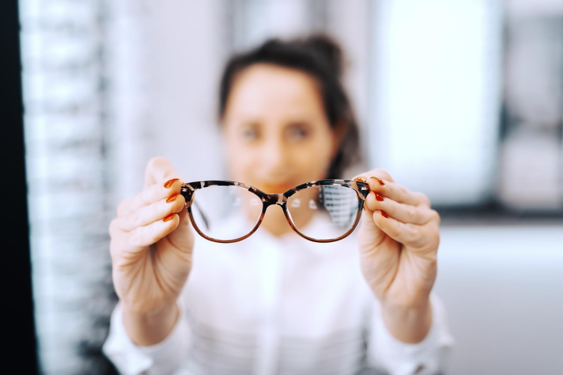 A woman is holding a pair of glasses in her hands.