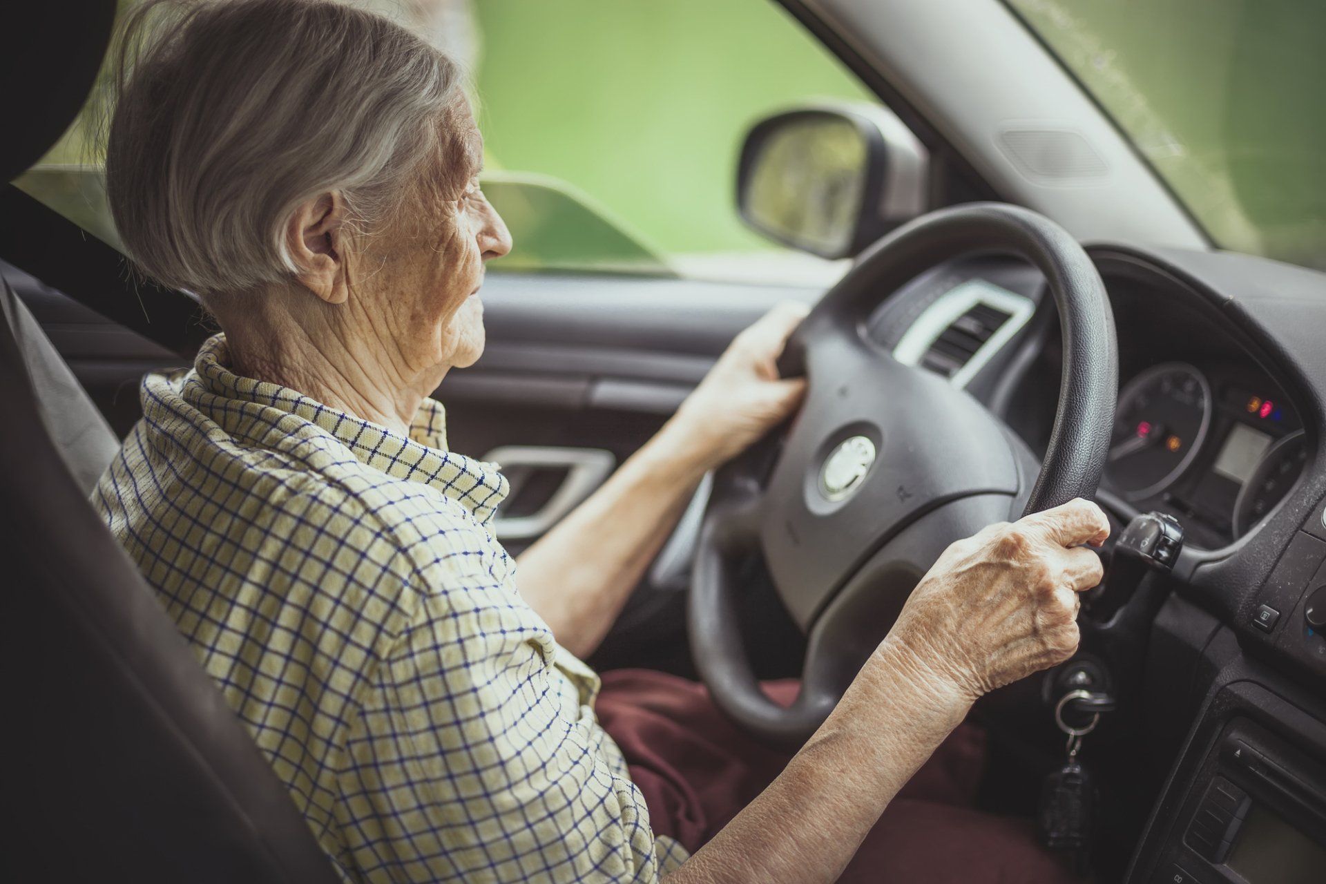 An elderly woman is driving a car.