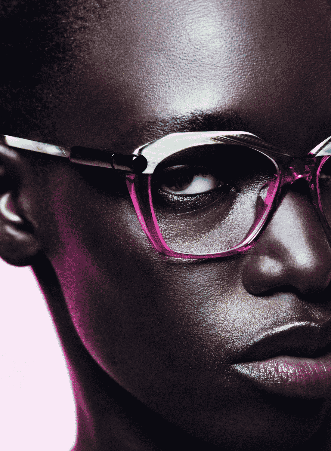 Close-up portrait of a person wearing pink-framed glasses against a light background