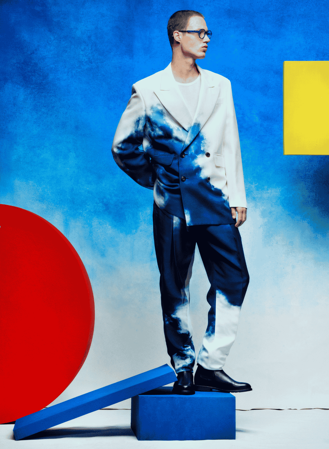 Stylish person in blue-and-white clothing standing on a blue block against a bright blue background