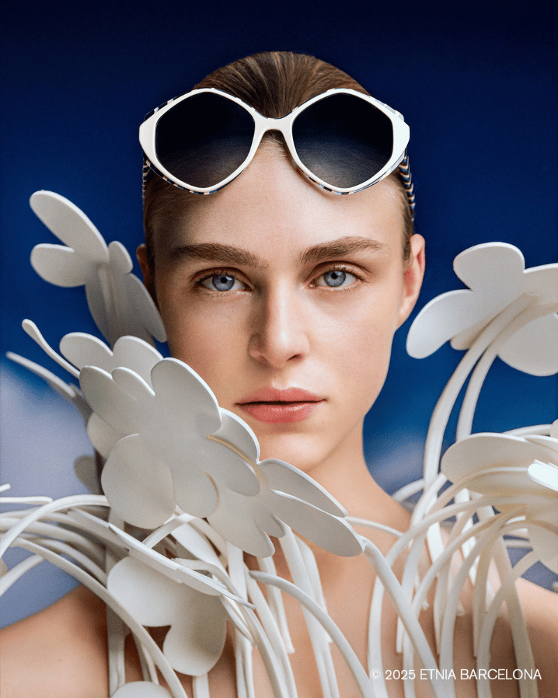 A woman wearing sunglasses is surrounded by white flowers
