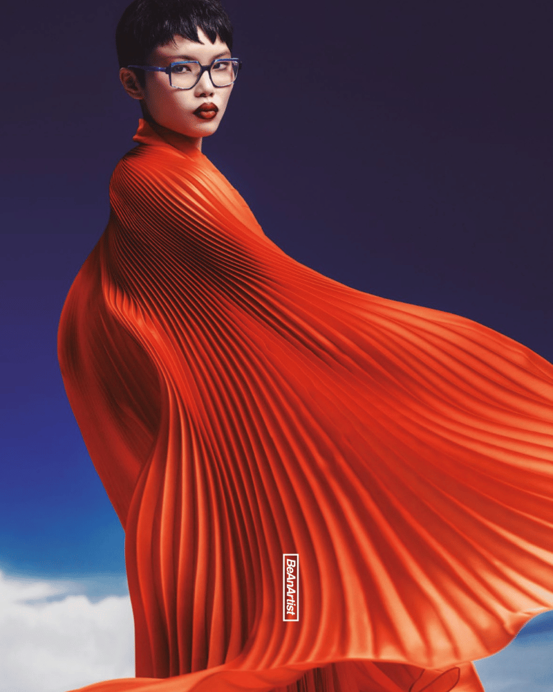 A woman wearing glasses and an orange pleated dress