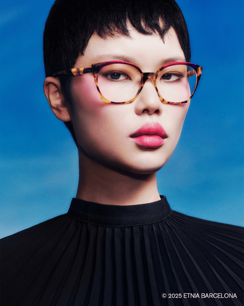 A woman wearing glasses and a black pleated top