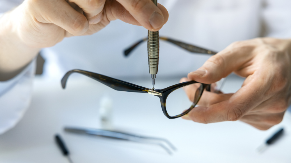 A person is fixing a pair of glasses with a screwdriver.